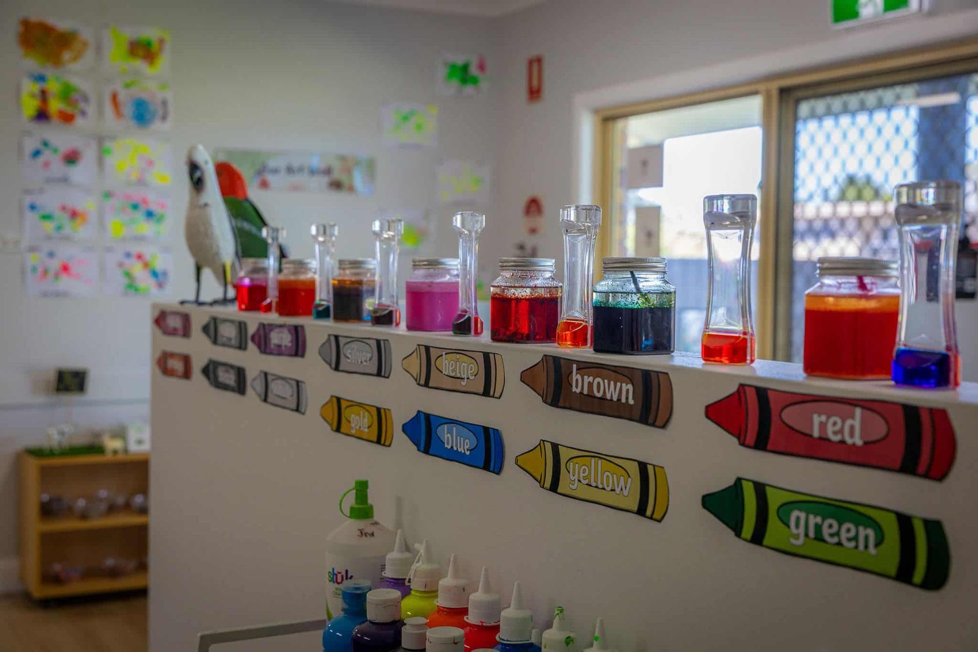 Colour-learning display with crayon labels and jars of coloured water