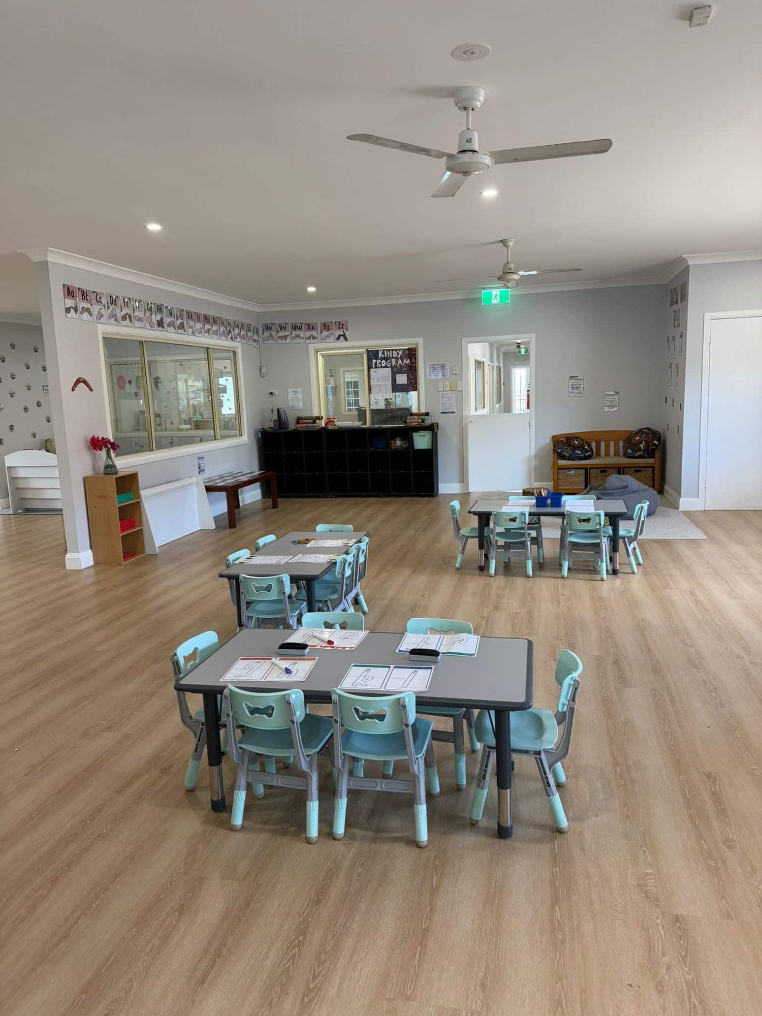The spacious kindergarten room with group tables, a reading area and children’s work on display