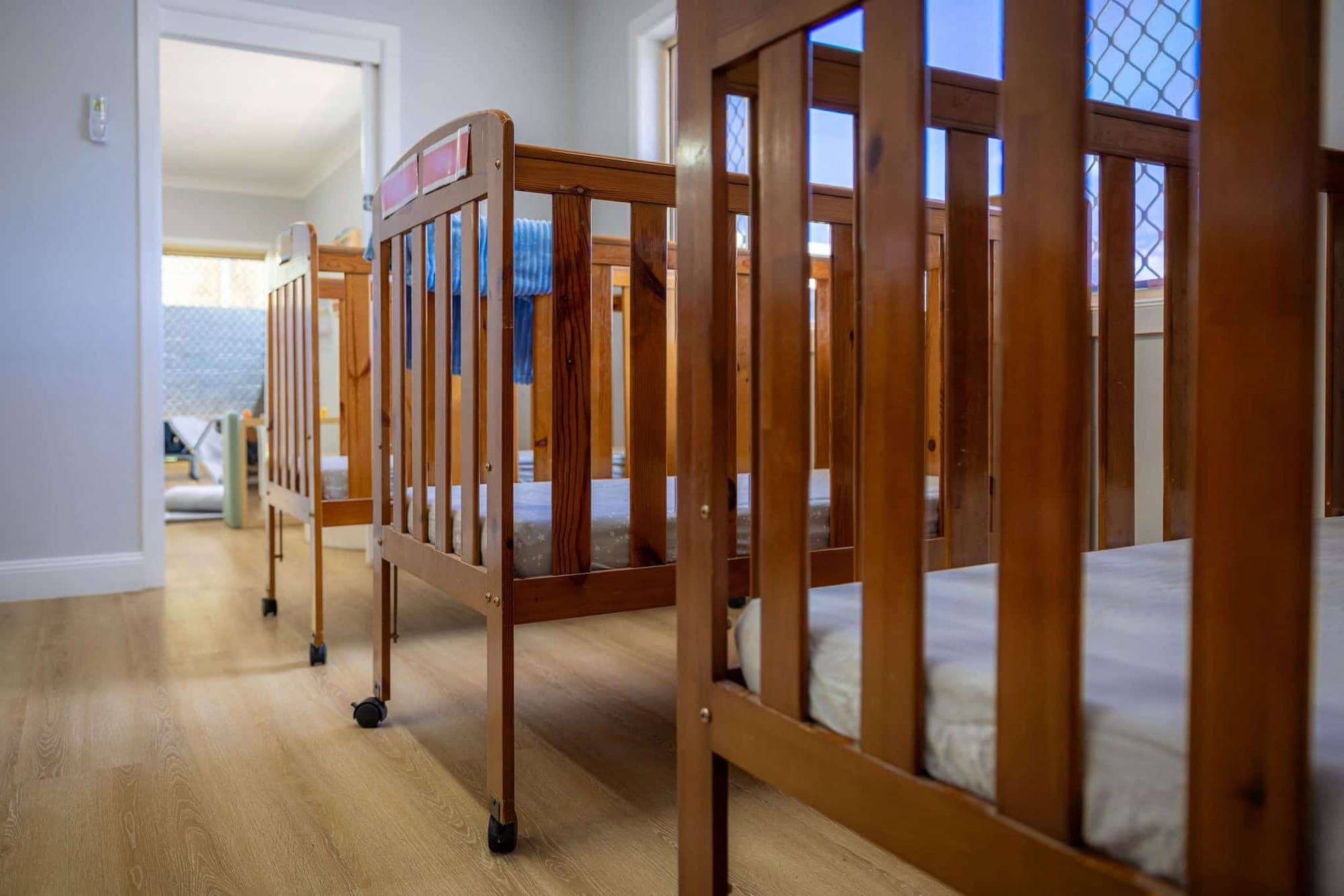 Row of timber cots in the quiet nursery sleep room