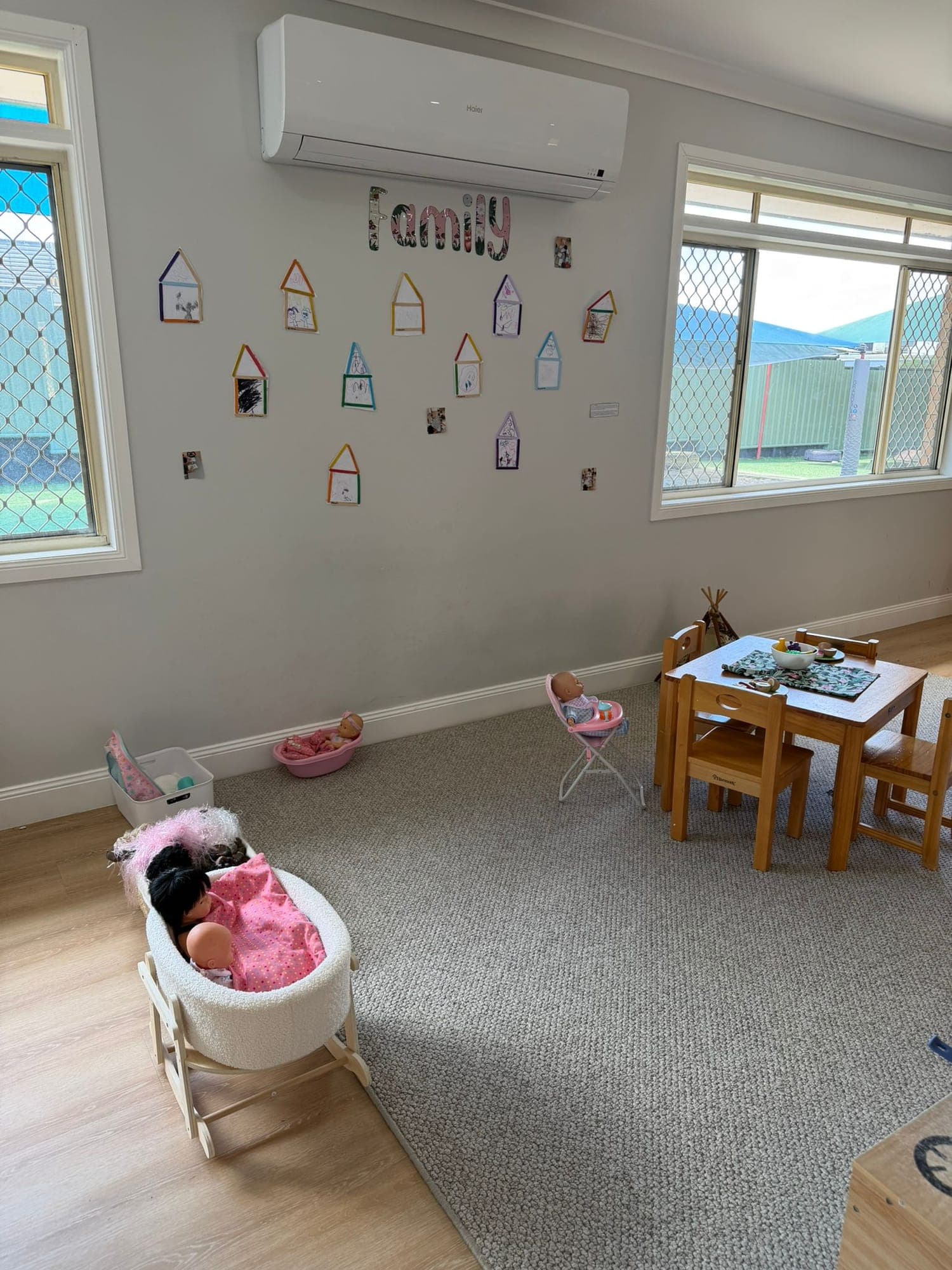 Bright nursery room with a play kitchen and children’s artwork on the walls