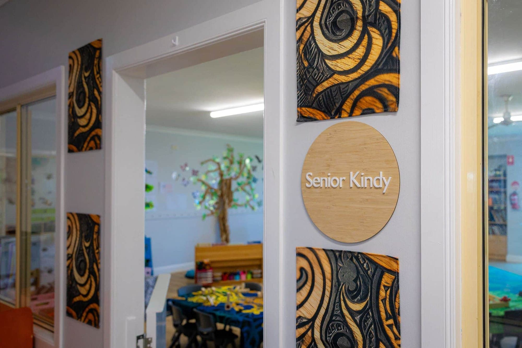 Timber Senior Kindy sign beside the open doorway, framed by bold patterned artworks