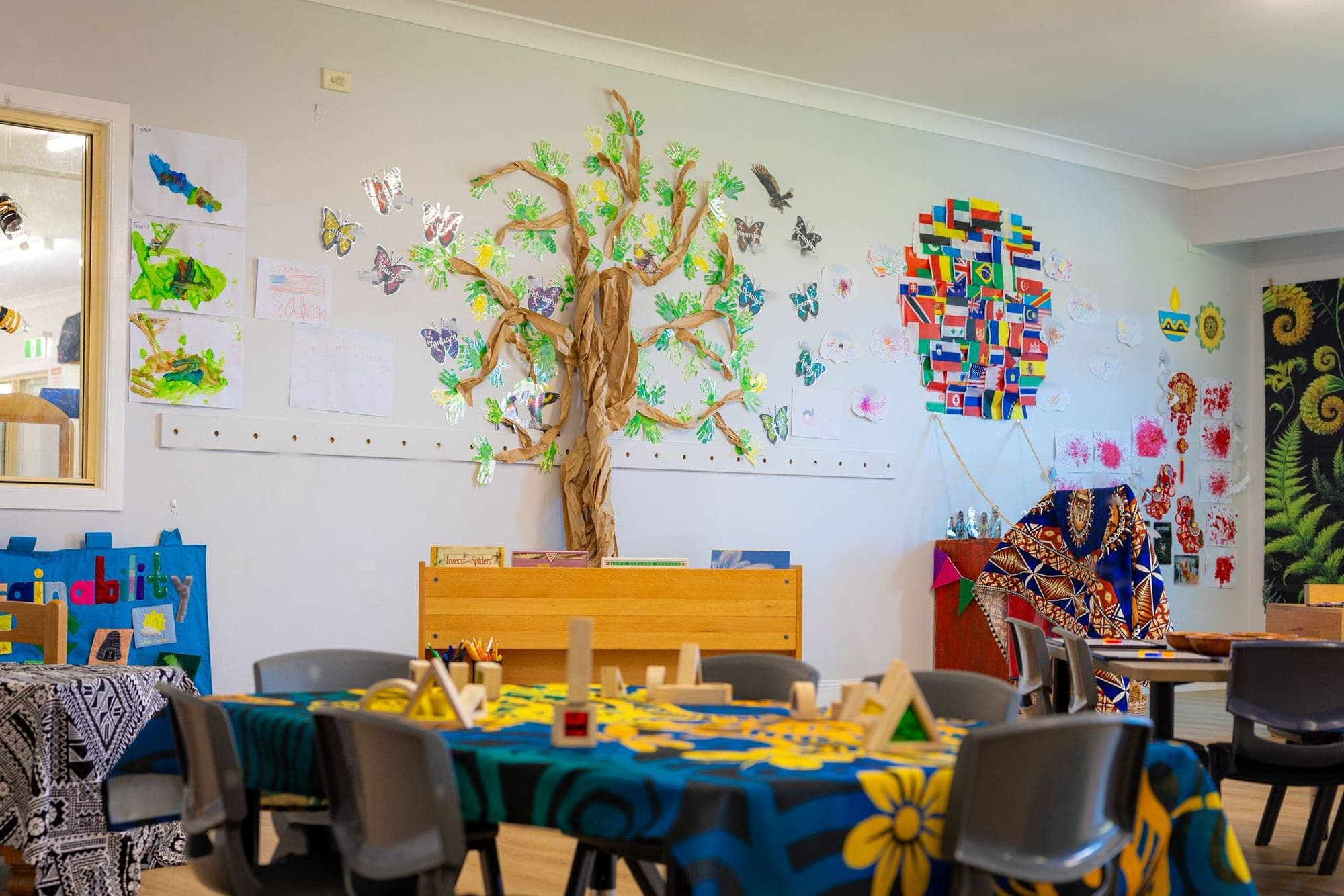 A painted tree mural with paper butterflies above children’s tables in Senior Kindy