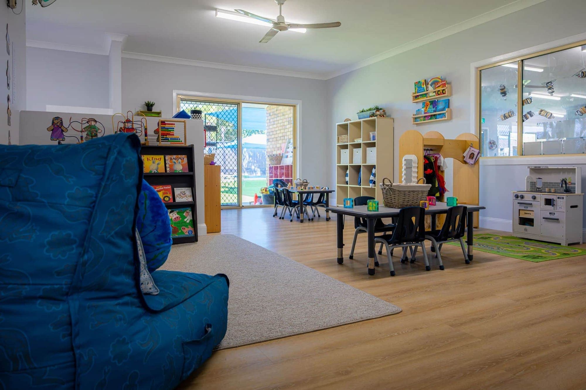 The toddler room with a soft beanbag, book shelves and a play kitchen